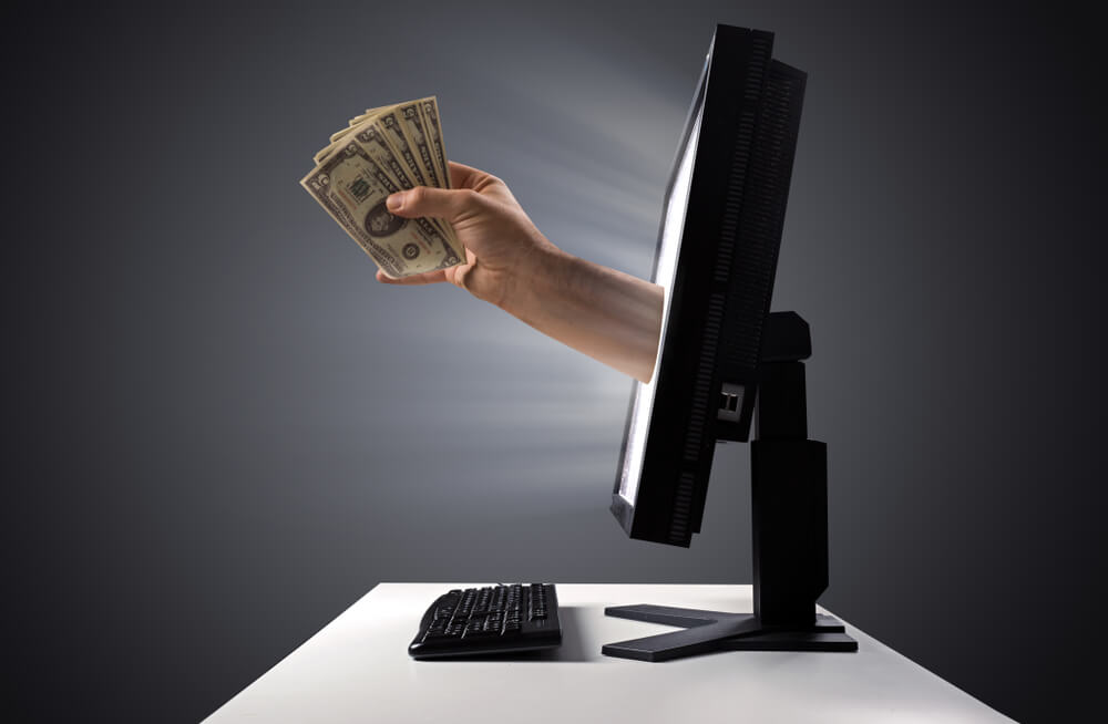 hand giving online title loan cash through computer