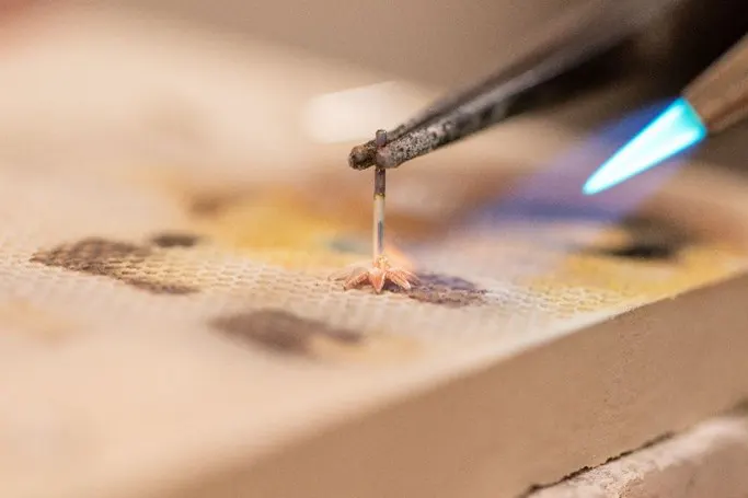 Close up of earing post being soldered to decorative element