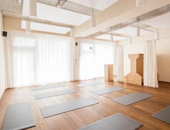 Helles Yoga-Studio mit großen Fenstern und viel Tageslicht, freier Blick nach außen und ruhige, offene Raumgestaltung für Yoga-Praxis und Entspannung.