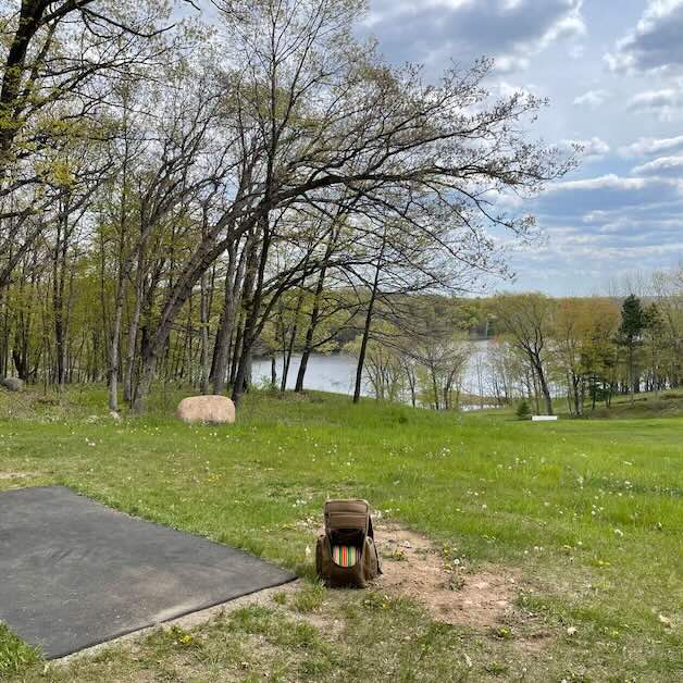 A rubber disc golf tee pad and a view of a lake beyond