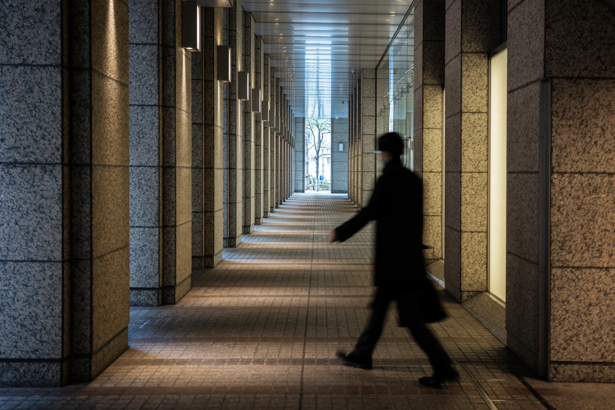 A person walking through a long, illuminated hallway in a modern building.