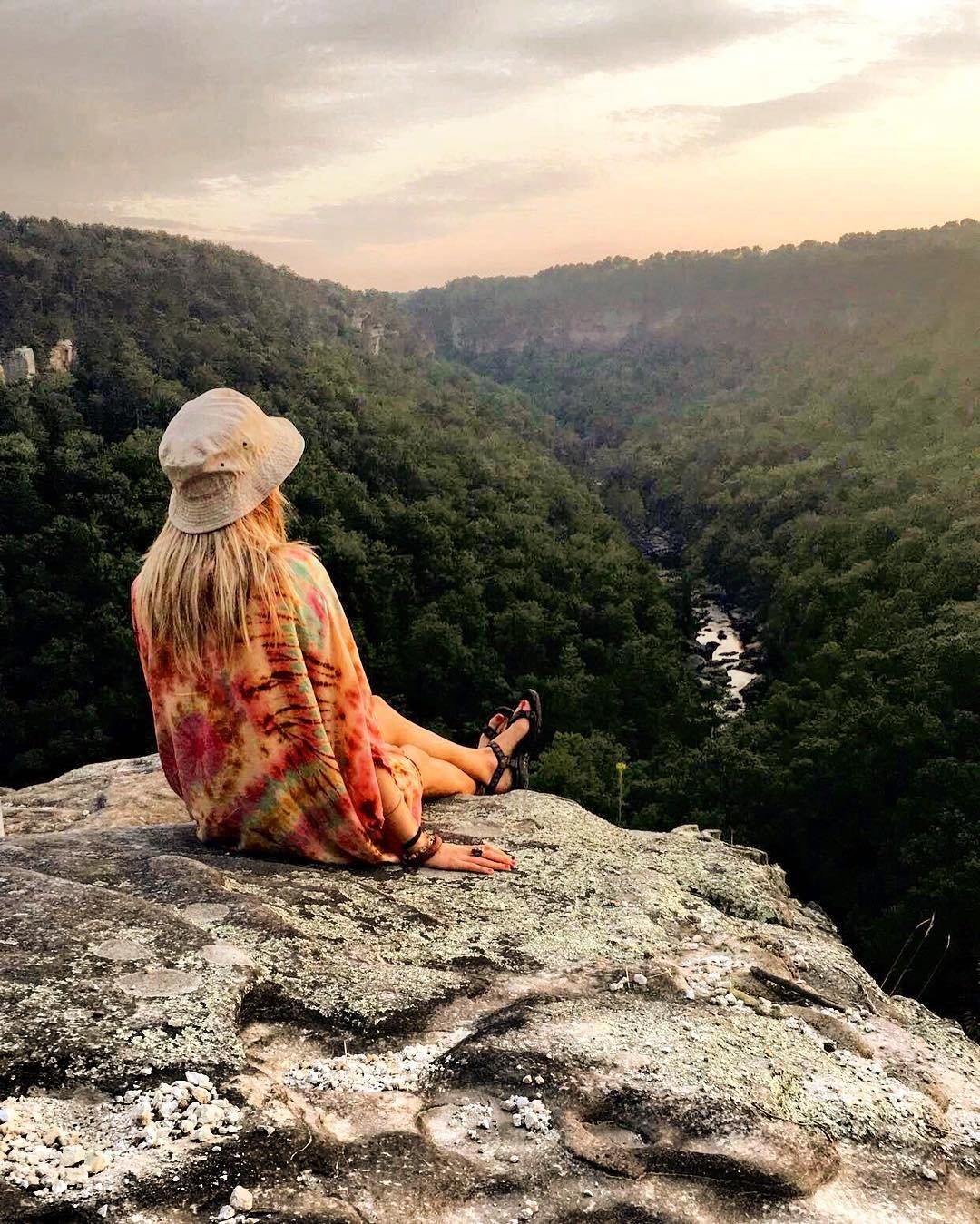 Girl sitting on rock overlooking beautiful mountain scenic view.