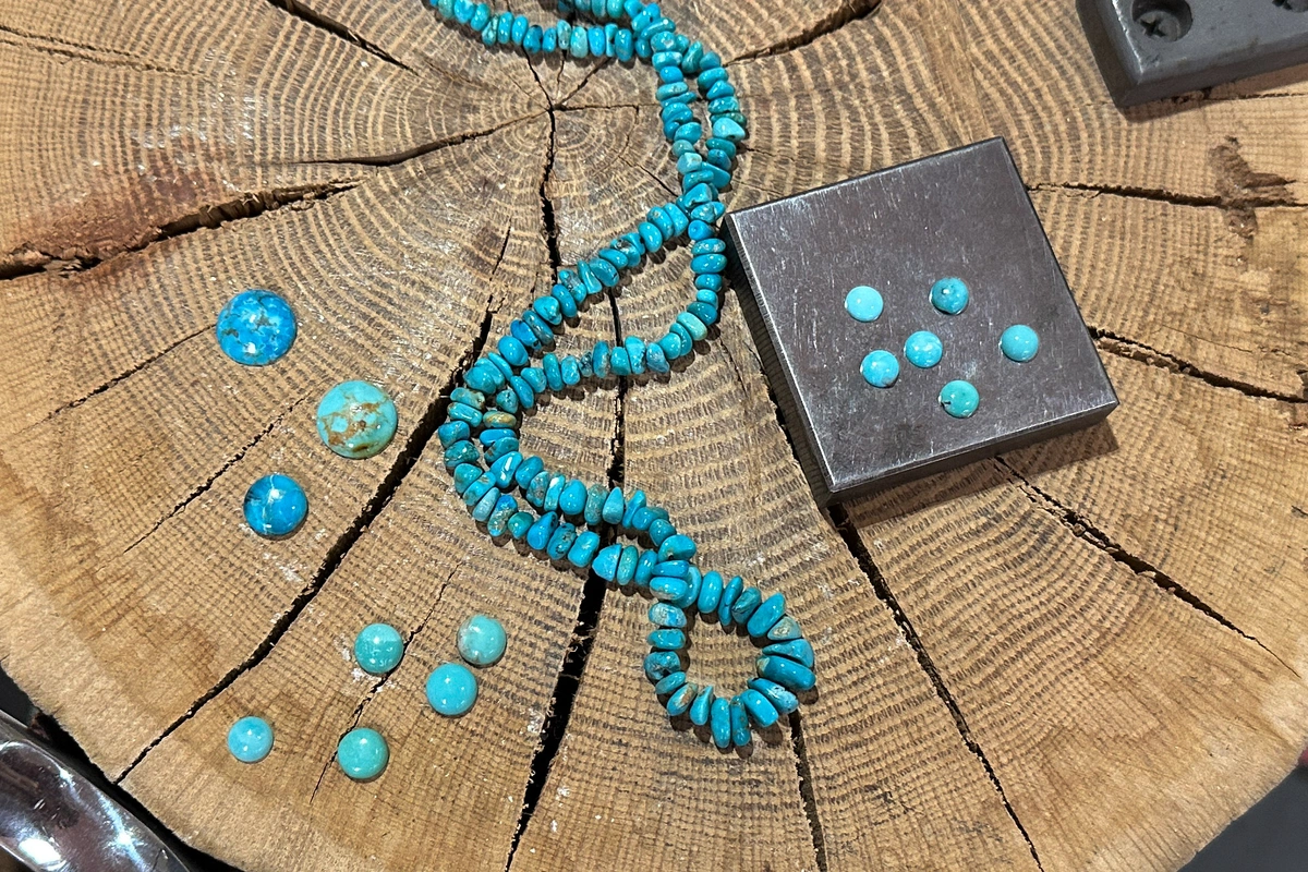 assorted turquoise cabs and beads on wood