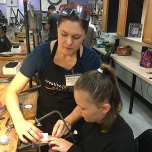 Lindsay helps her student with sawing at a bench