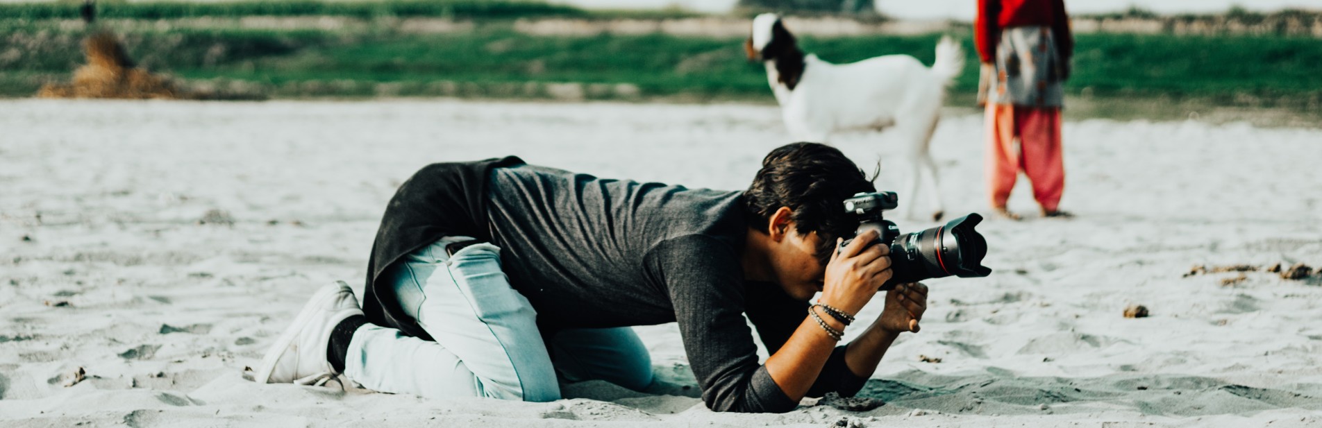Photographer kneeling on a beach while taking a photo