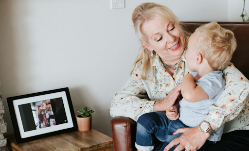 Grandma and grandson smiling and seated next to digital photo frame