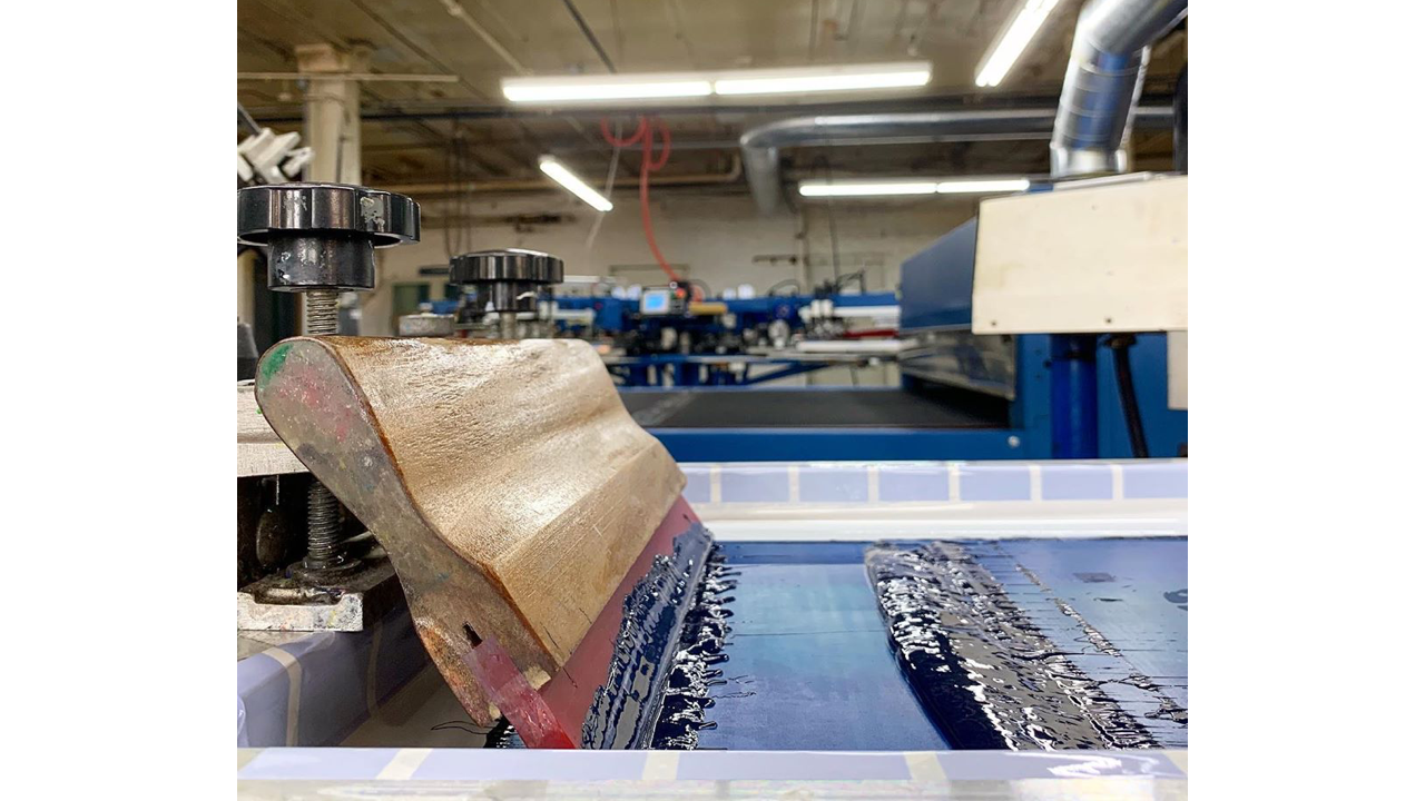 A squeegee sits on top of a screen for screen printing.