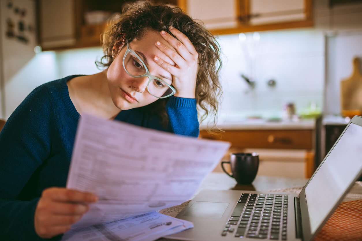 Woman looking at a bill with a stressed expression