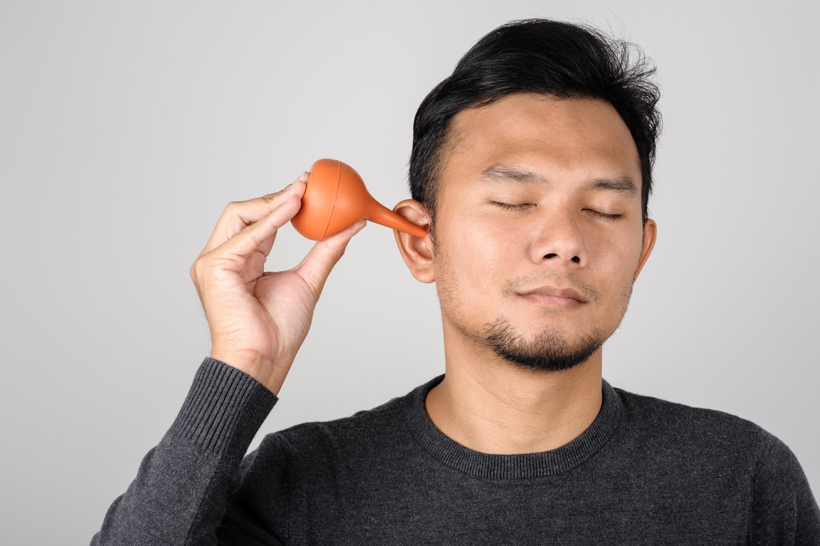 How to improve hearing: A man uses a rubber syringe to clean his ears