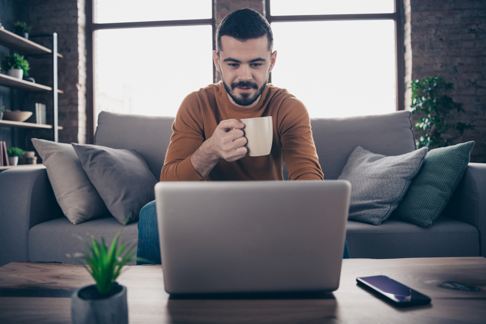 man on laptop at home drinking tea