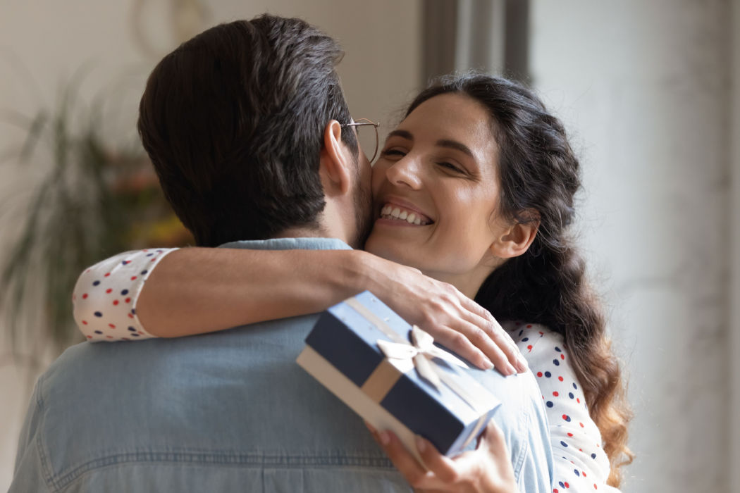 A Hispanic woman shows how to be more grateful by hugging her partner after receiving a gift.
