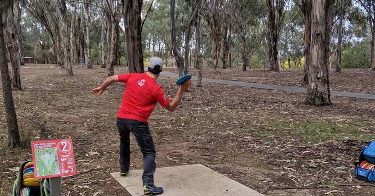 A player throwing a forehand on a wooded hole