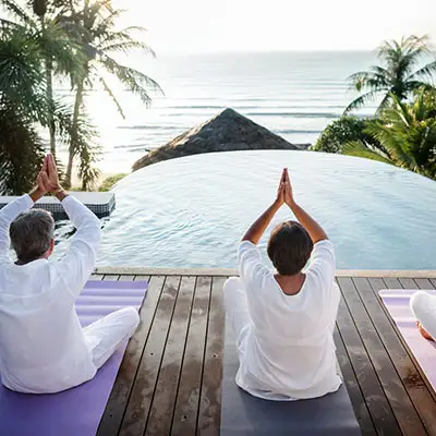 Older couple doing yoga waterfront view.