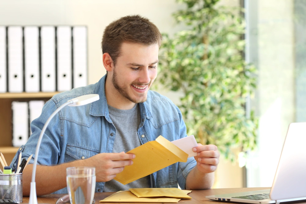 smiling man at desk with envelopes