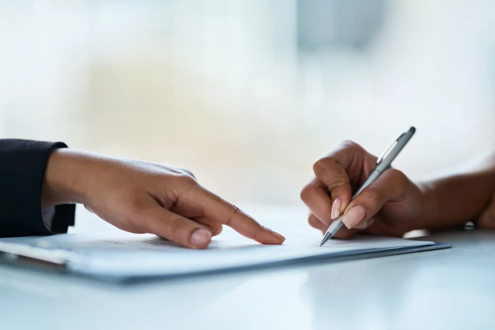 Two people reviewing and signing a document during a business discussion
