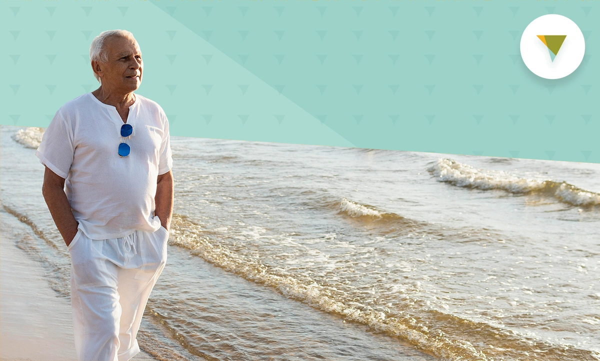 Elderly man in white walking along the beach