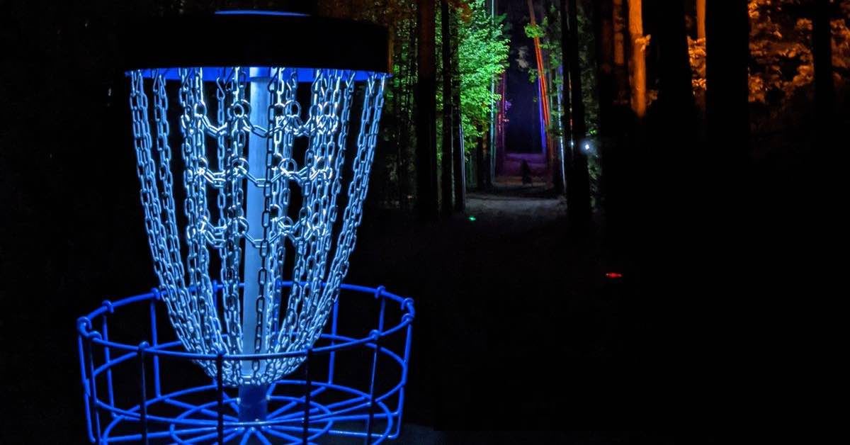 A disc golf basket lit up at night at Blue Ribbon Pines in Minnesota