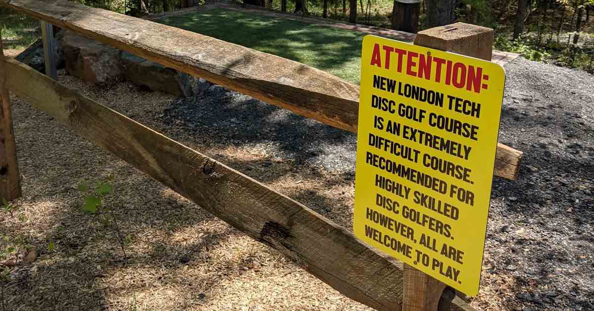 A yellow sign on a fence warning players of a course's difficulty