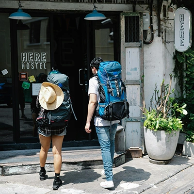 Couple of travelers with backpacks entering hostel.