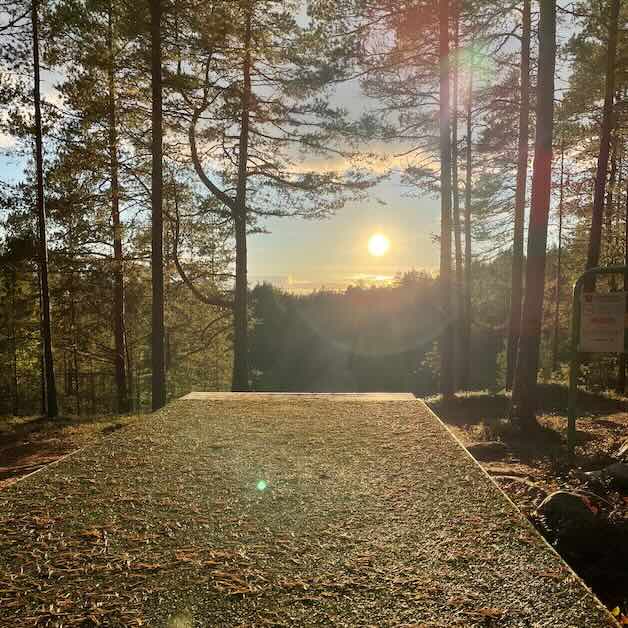 A disc golf tee in an elevated place with sun shining directly into the camera