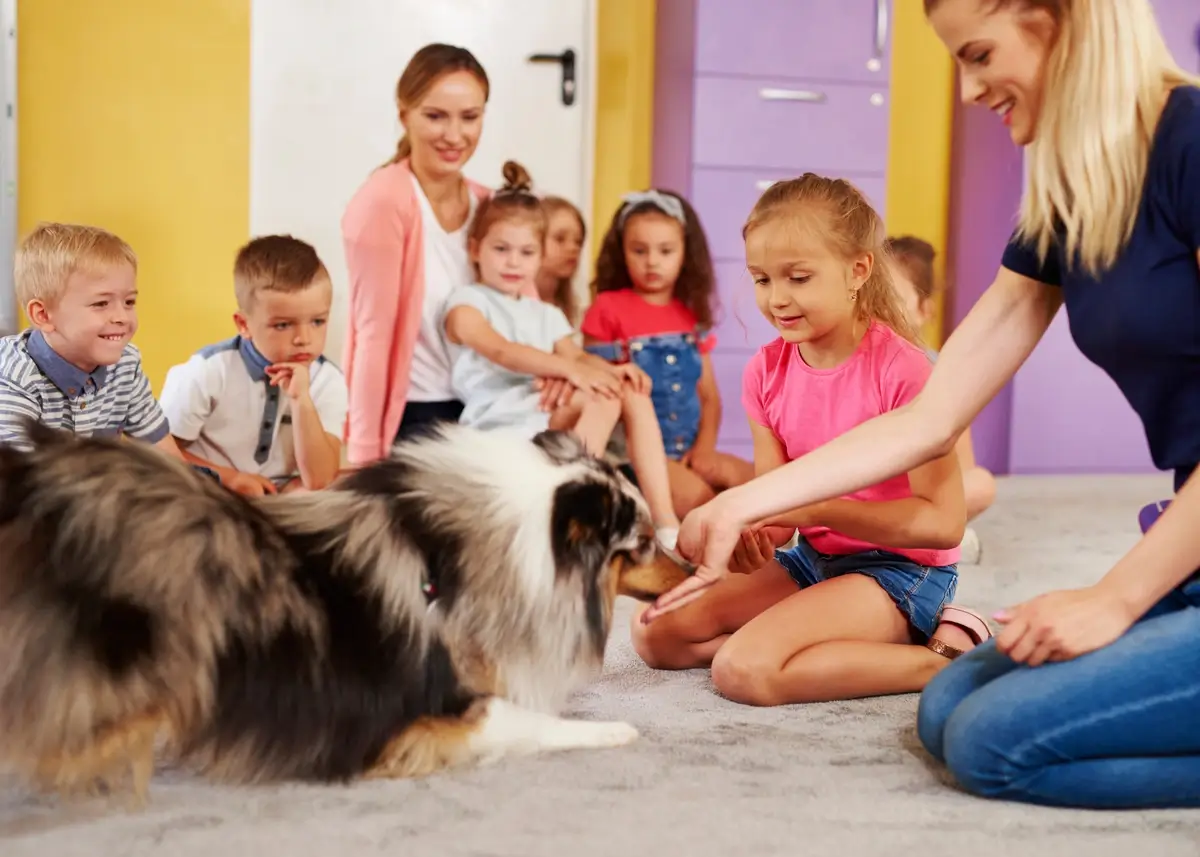 Seated children gather around a furry dog