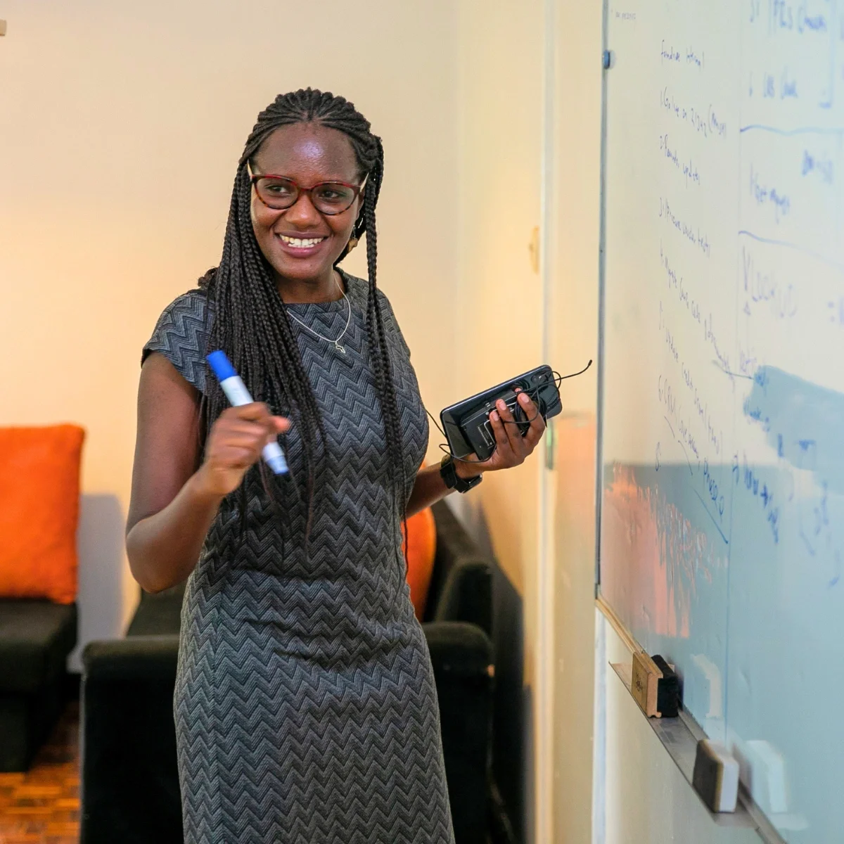 A young woman in professional wear standing and writing on a large whiteboard, Entrepreneur tour Kenya, 2017.