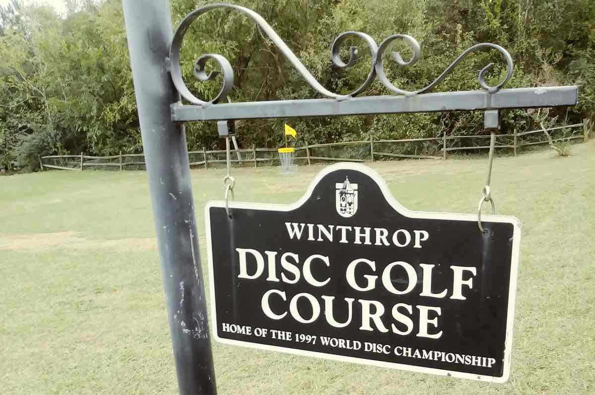 A black sign with white print saying "Winthrop Disc Golf Course"