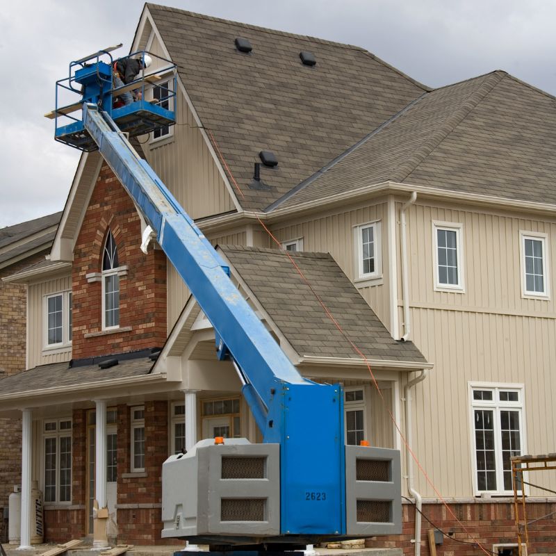 Blue straight boom lift working on windows on a residential home