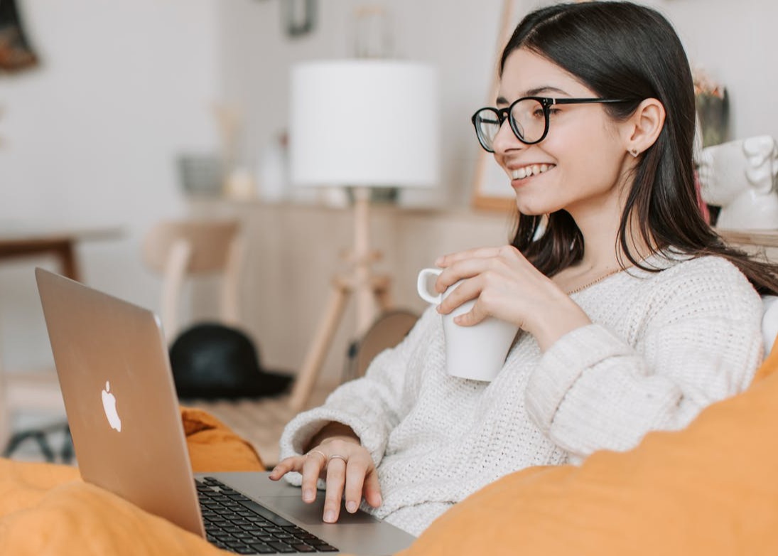 Woman using full fibre broadband to browse the internet while relaxing at home with coffee.