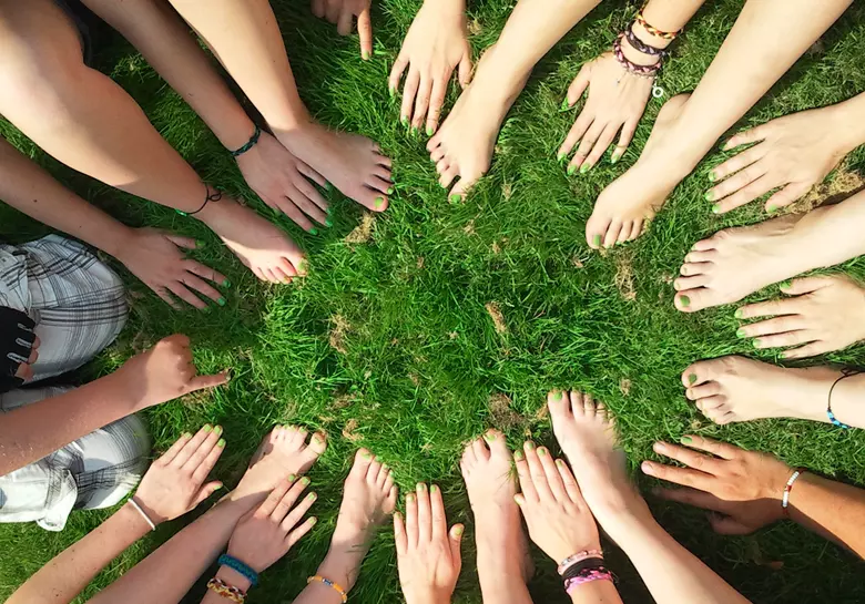 Many hands and feet touching green grass on the floor