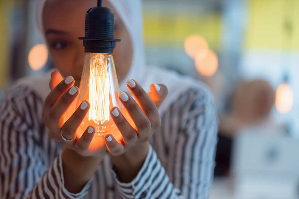 A lady cups her hands round a designer lightbulb