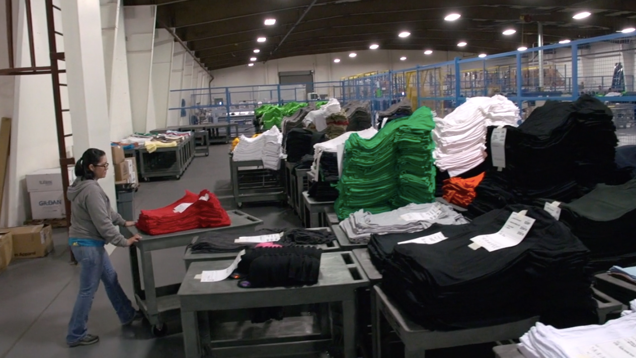 A worker in a screen printing shop sorting t-shirts.