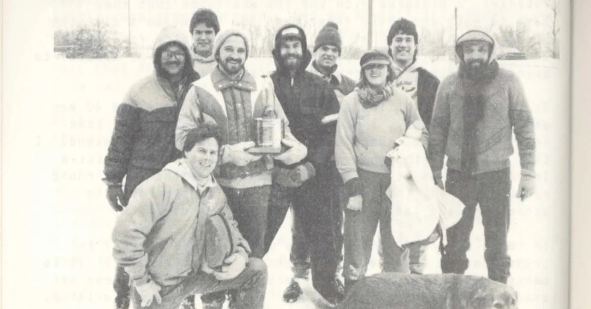 A black and white photo of a snowy outdoor scene with people posing for the camera