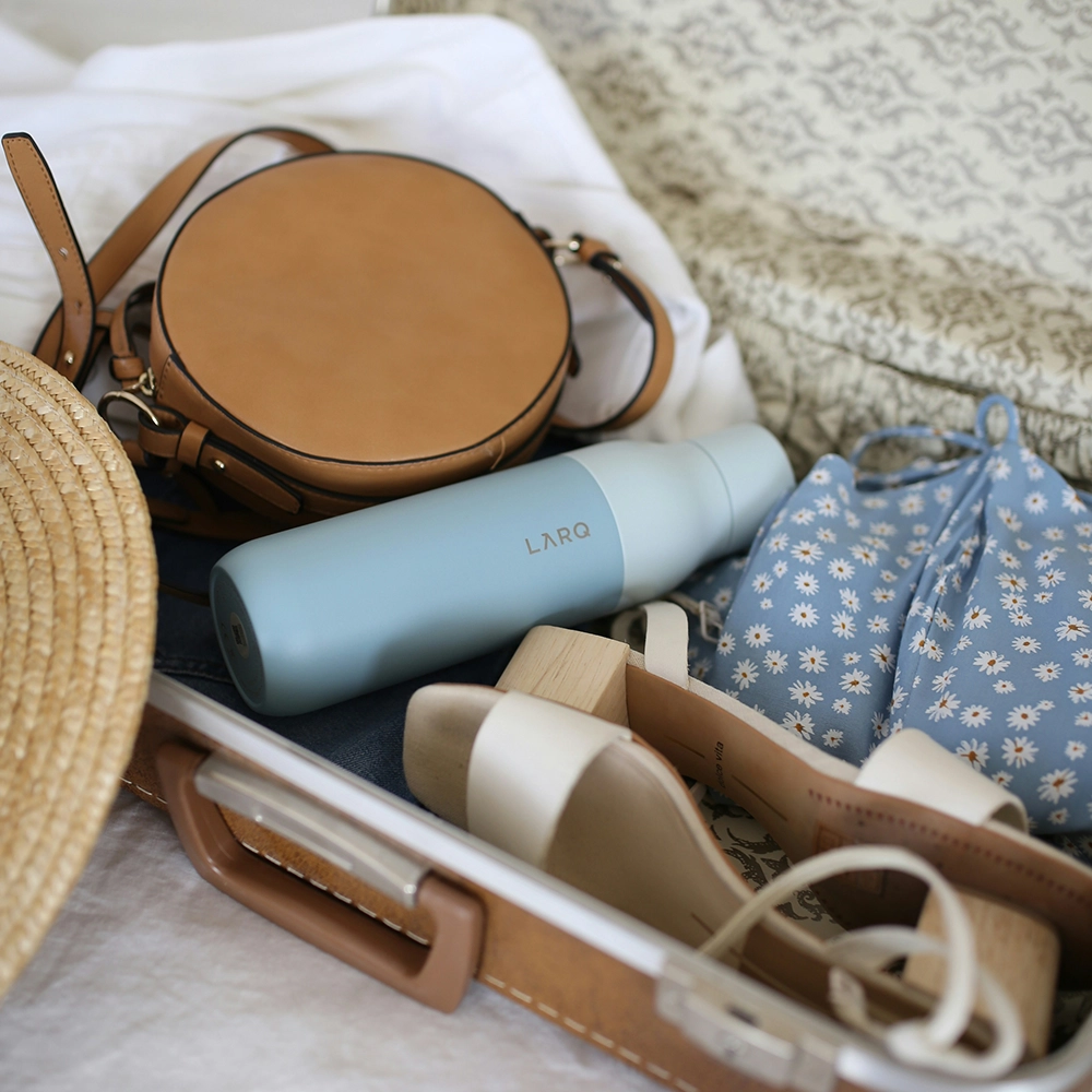 Packed suitcase with water bottle, shoes, and more.
