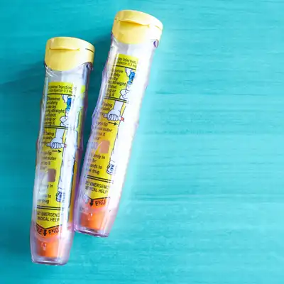 Two EpiPens on a blue background.