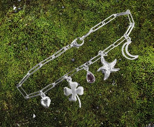 silver charm bracelet on moss with heart, clover, starfish, moon and purple teardrop stone