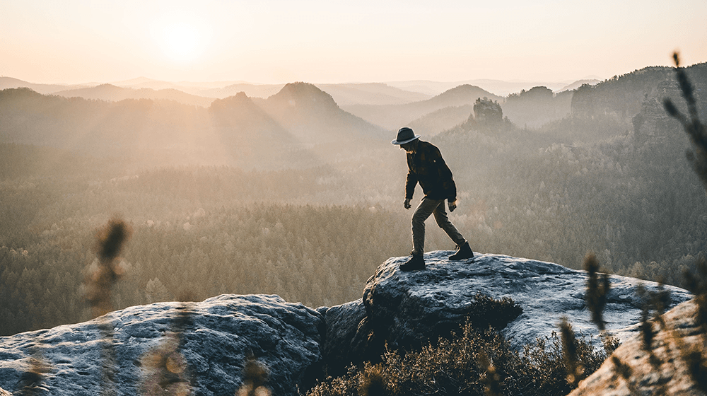 Man hiking on rock at sunrise