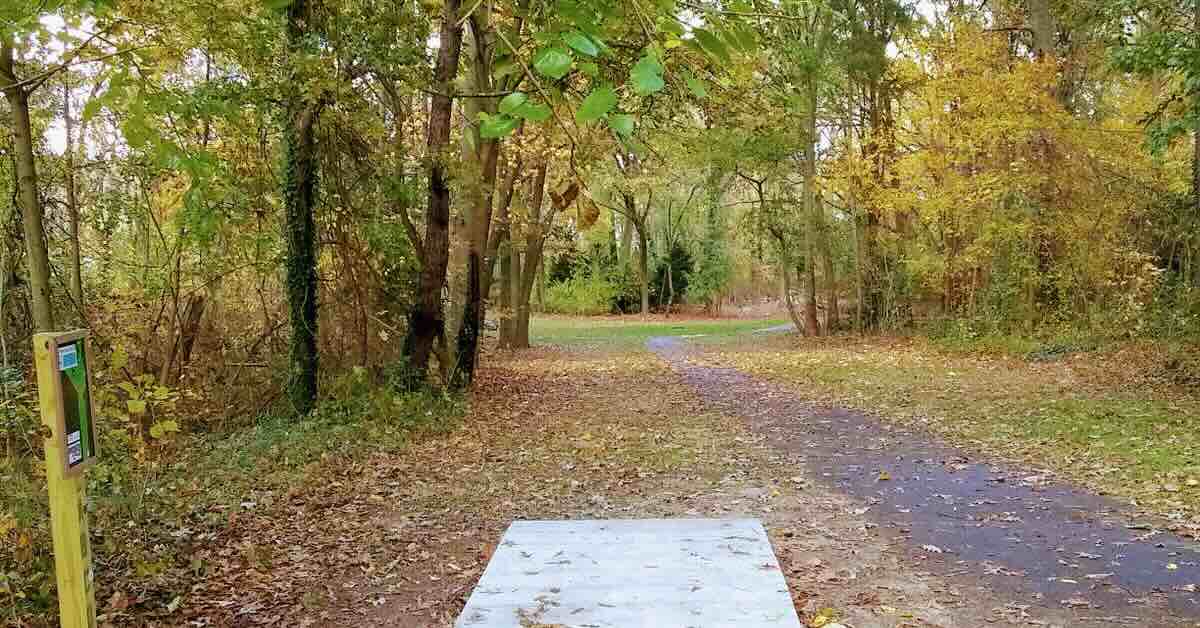 A concrete disc golf tee pad in a wooded area