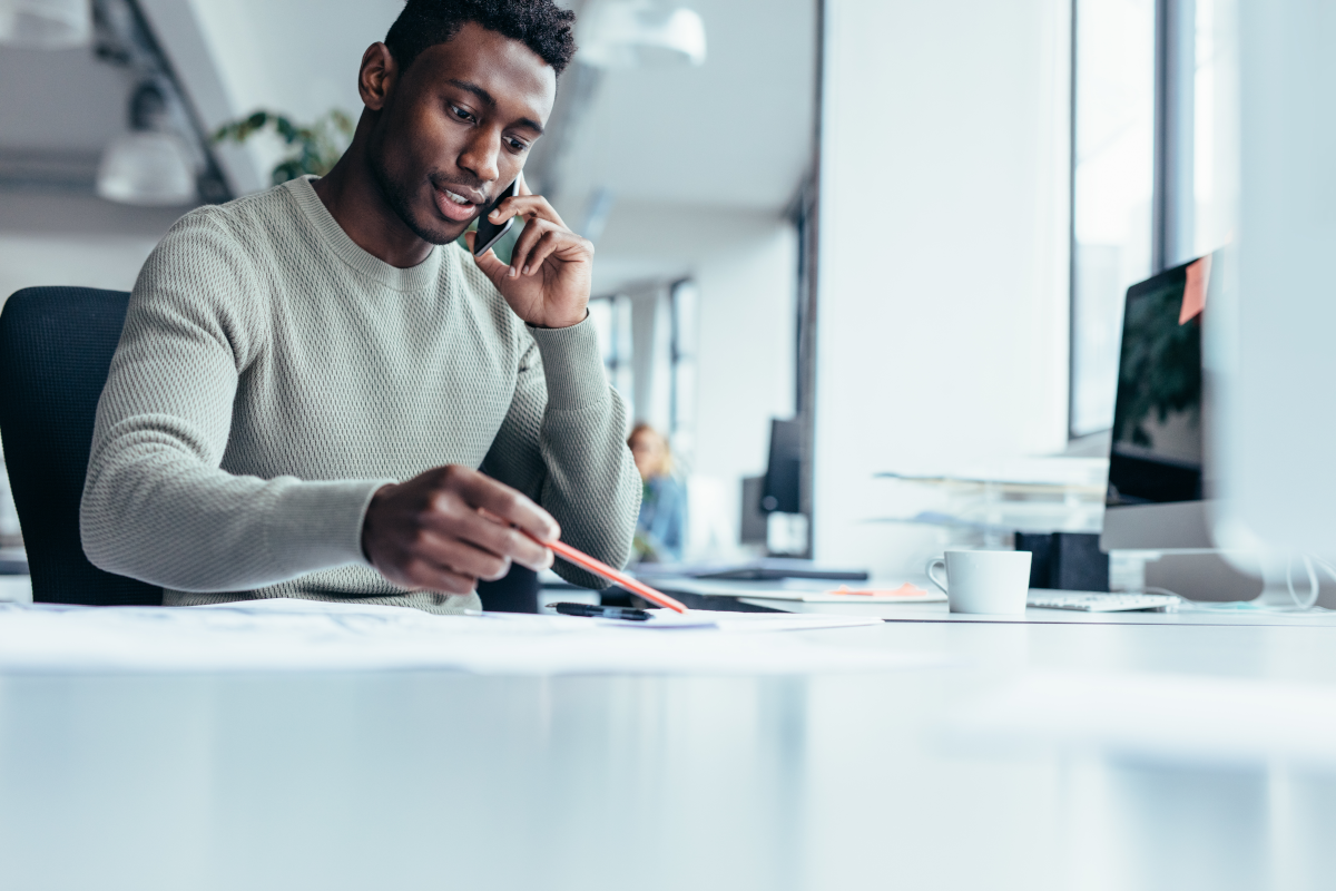 Man on mobile phone pointing at his desk