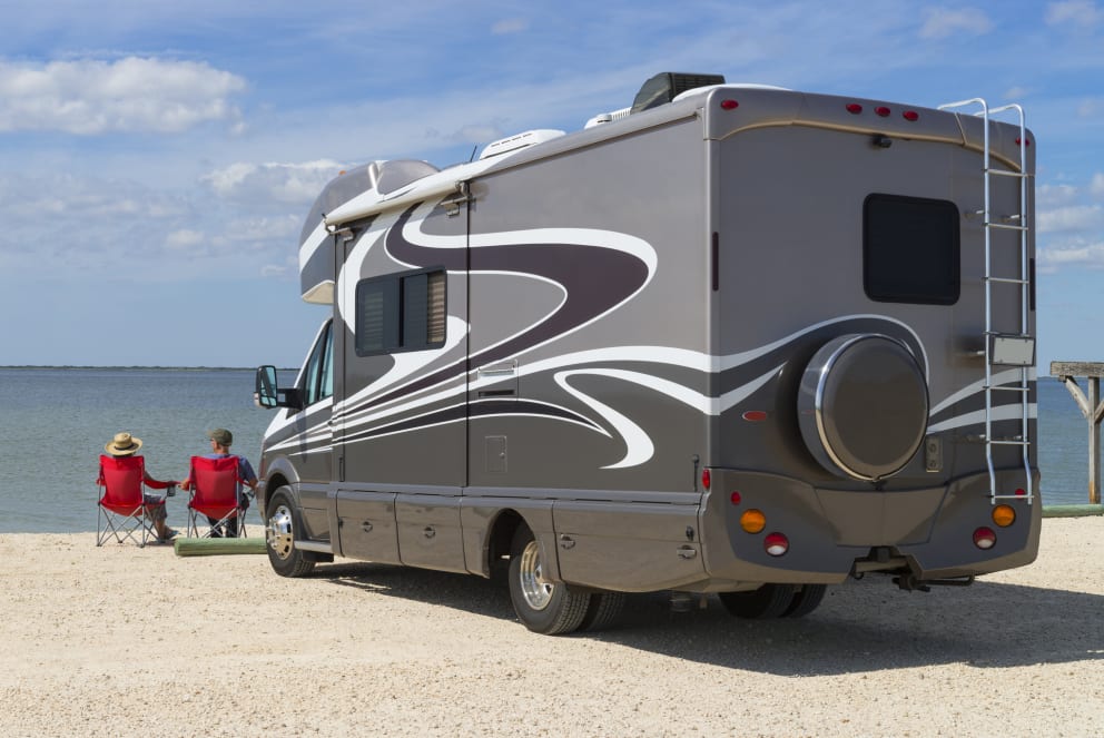 couple sitting beside their rv on the water