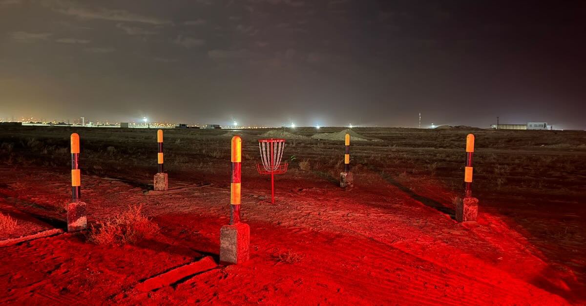 A basket in an desert landscape illuminated with red lights and surrounded by traffic poles