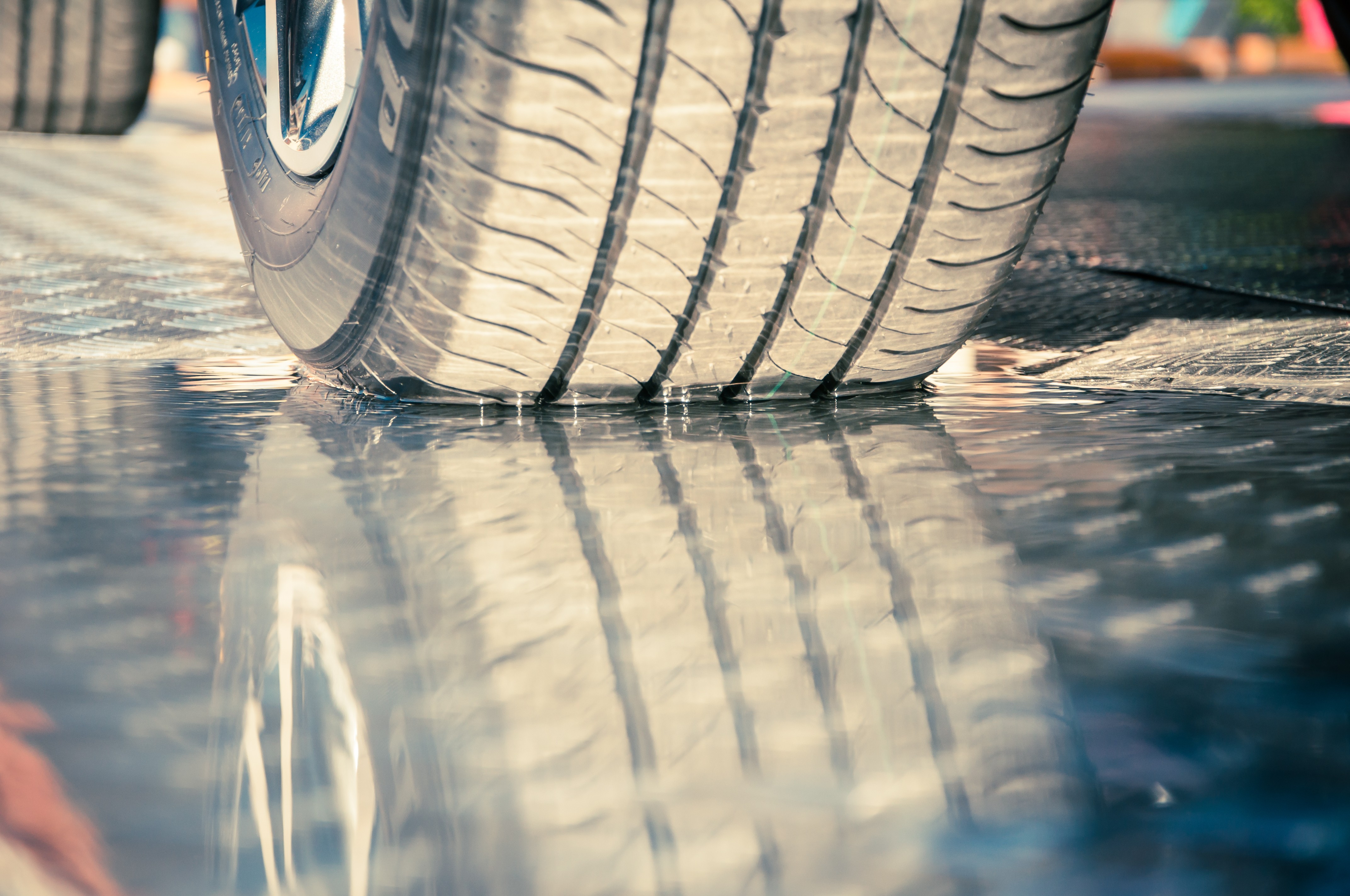 closeup of tire on wet pavement” width=