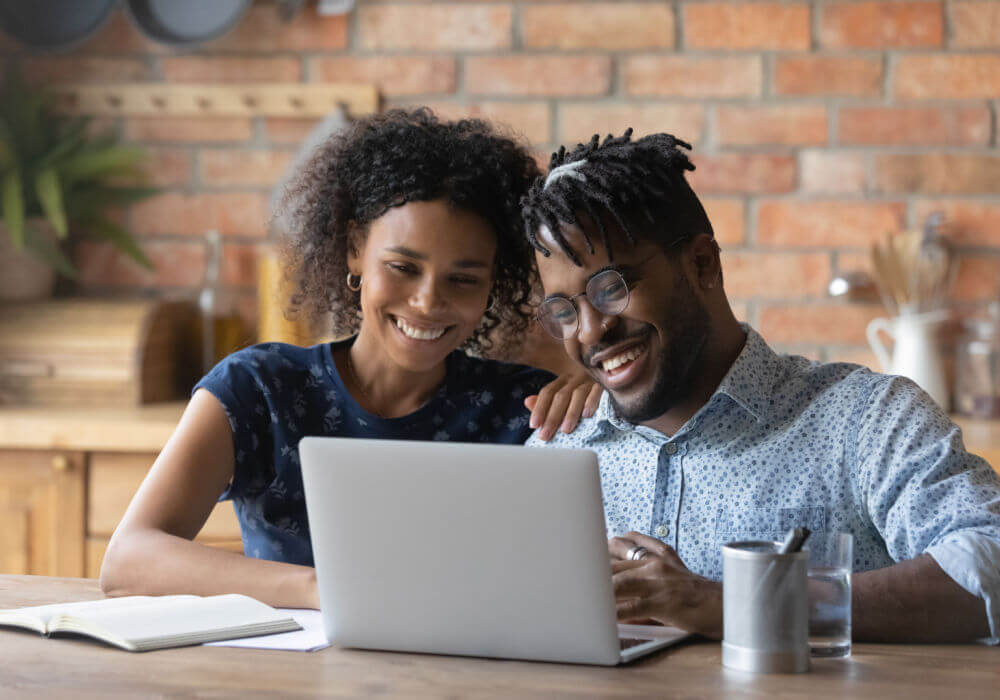 A black couple smiles while they learn about how to get a loan against car title online.