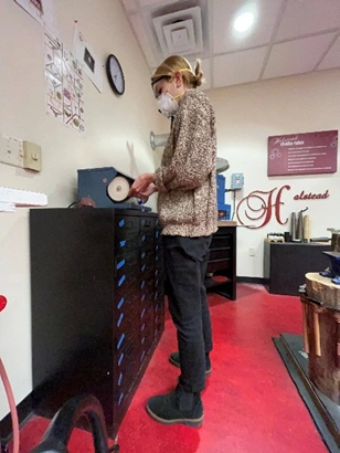 image of a girl in a sweater polishing jewelry at a bench top polisher