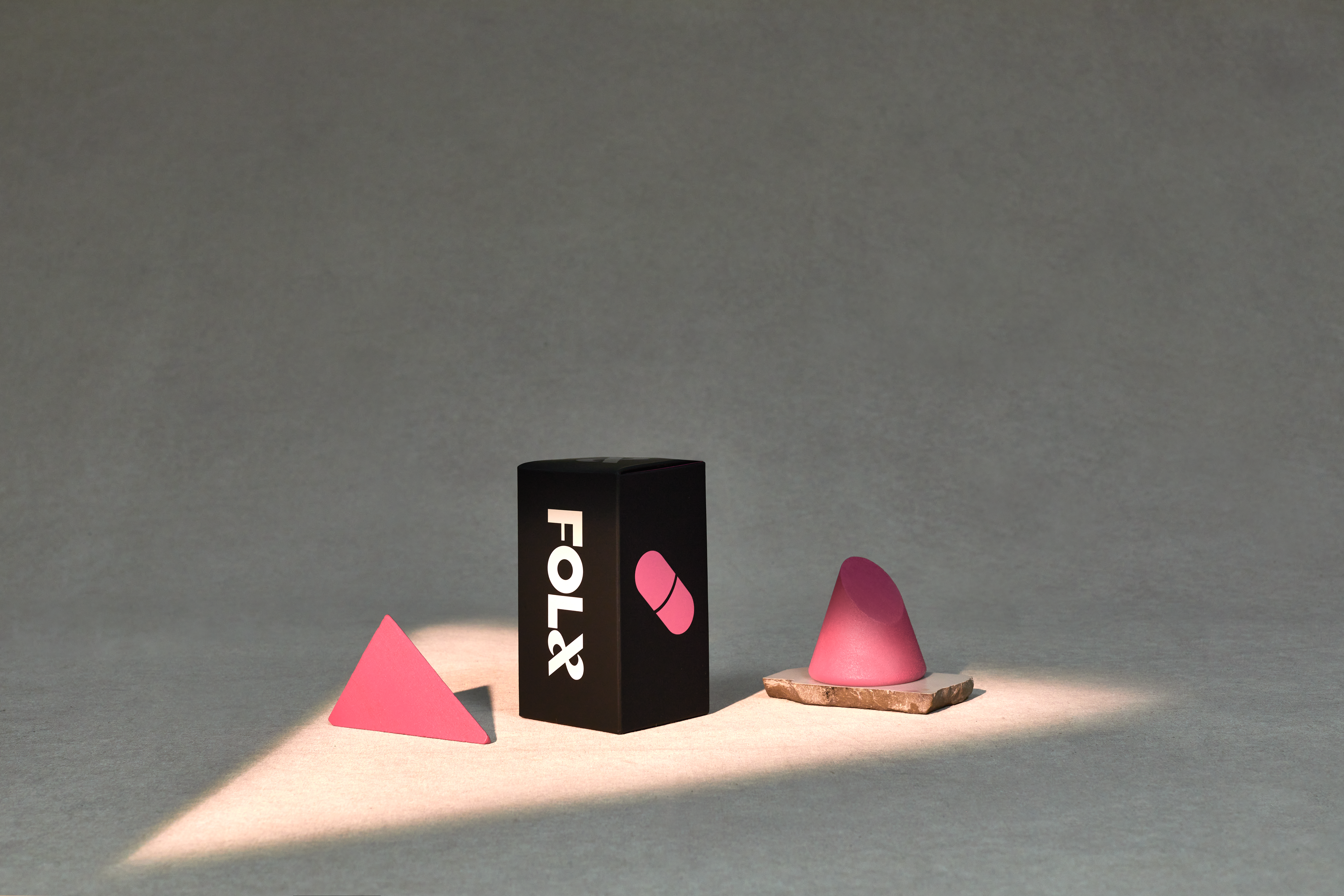 A triangular light over a pink triangle, a black box of FOLX PrEP, and a pink object