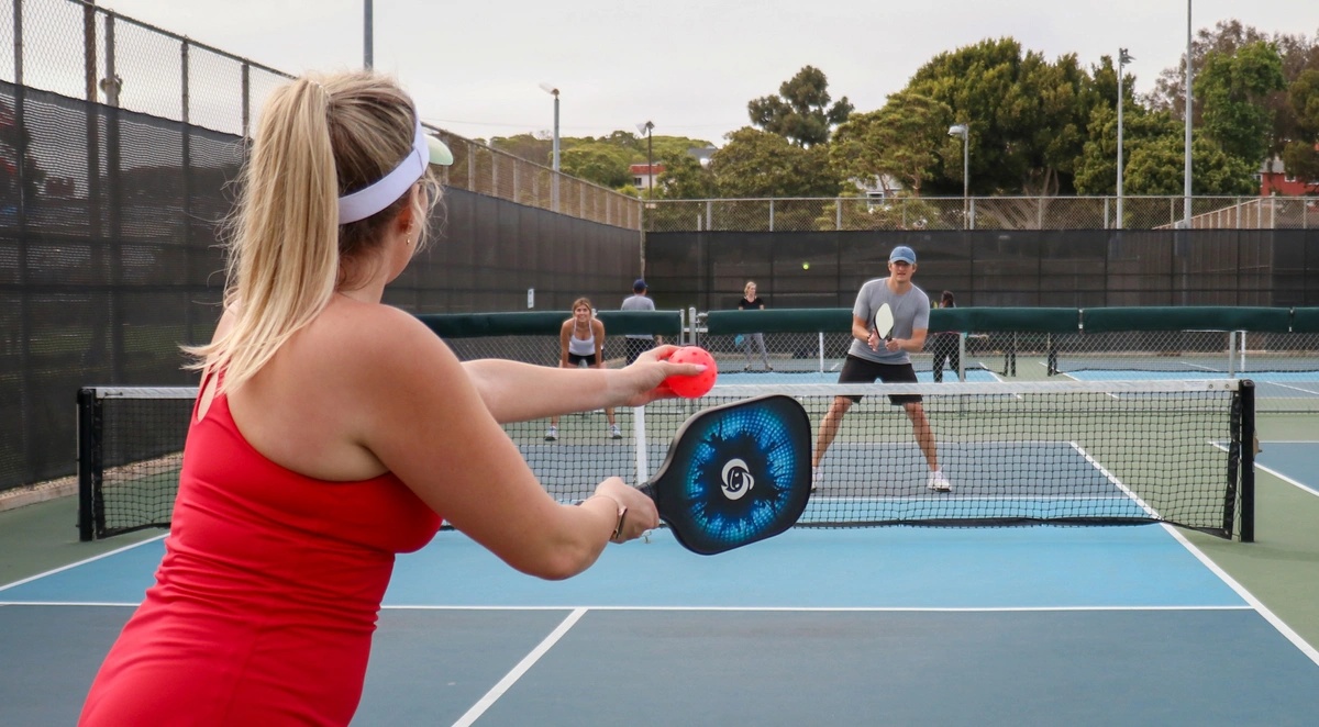 A woman serving in a pickleball game