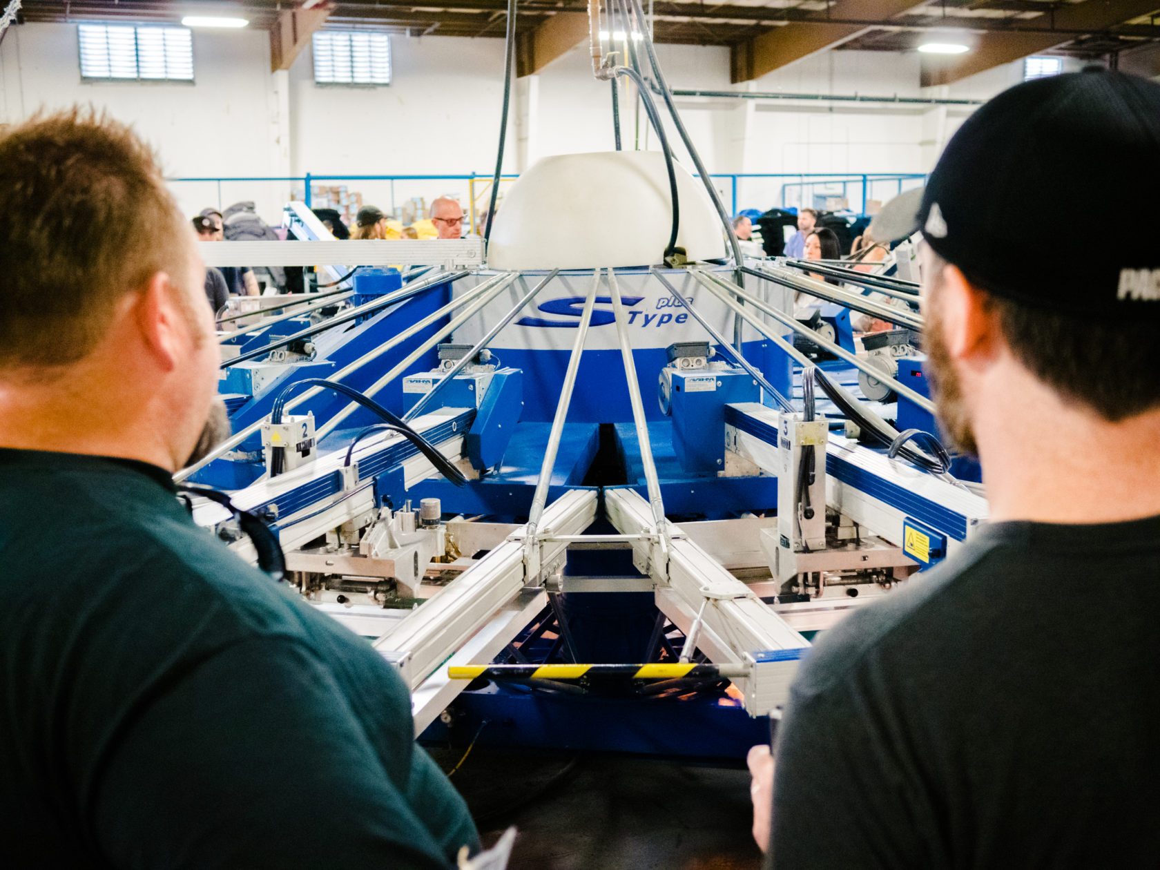 MHM screen printing press in operation as two people look on.