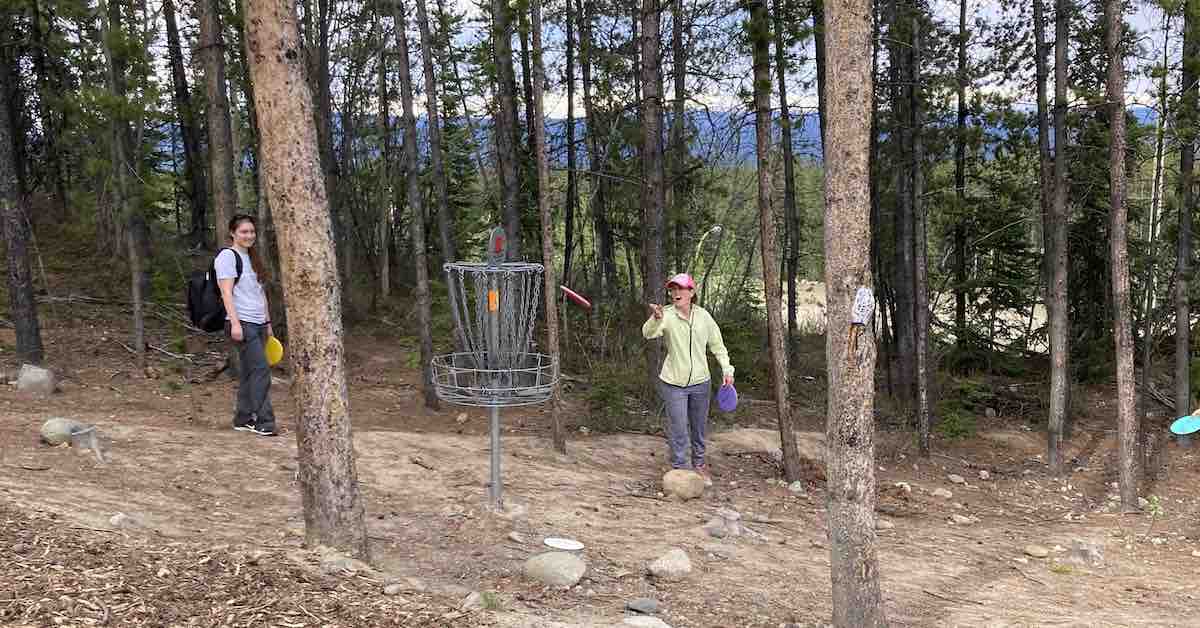 One woman putting on a disc golf basket on a mountain course