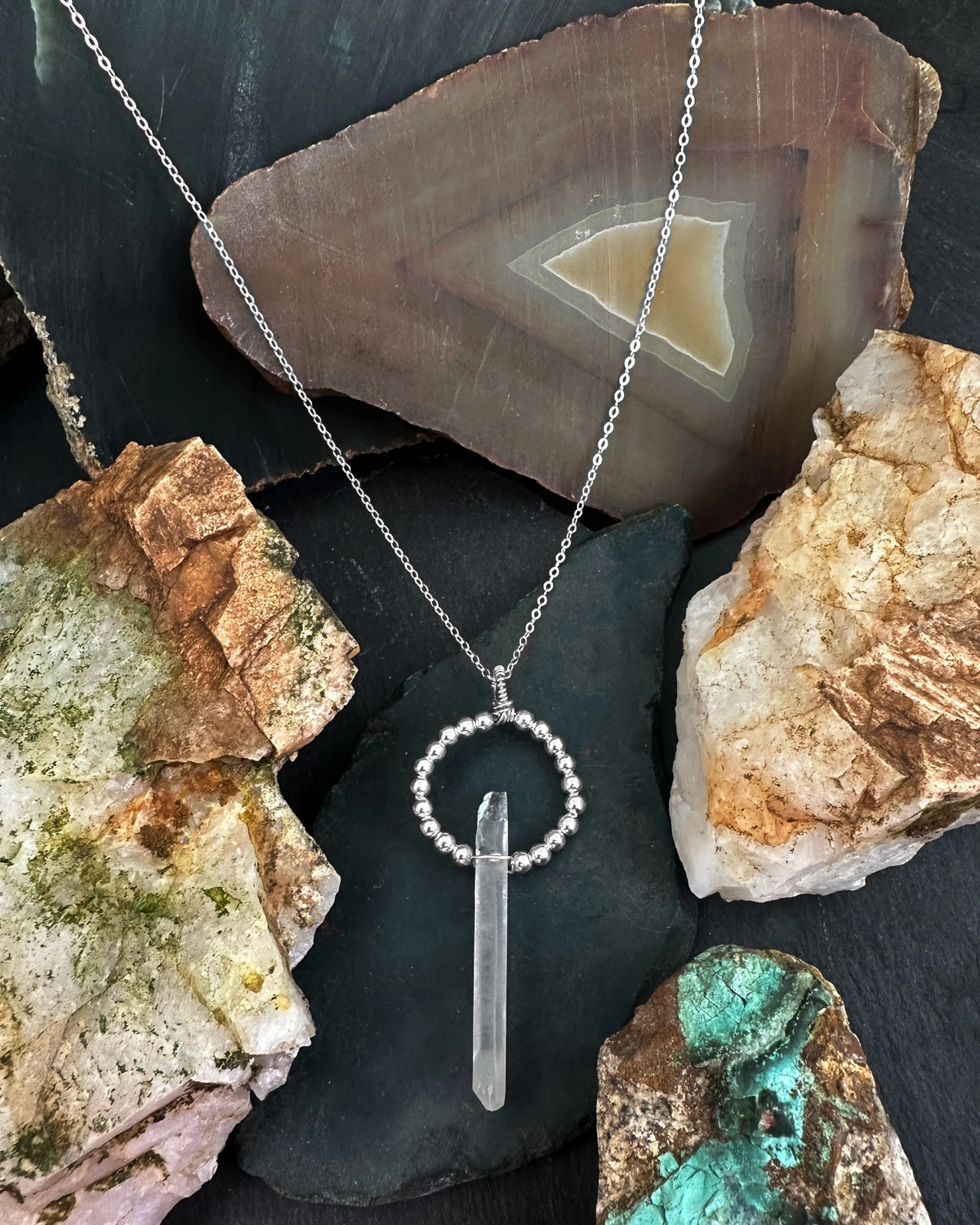 crystal drop necklace with silver bead halo surrounded by rocks