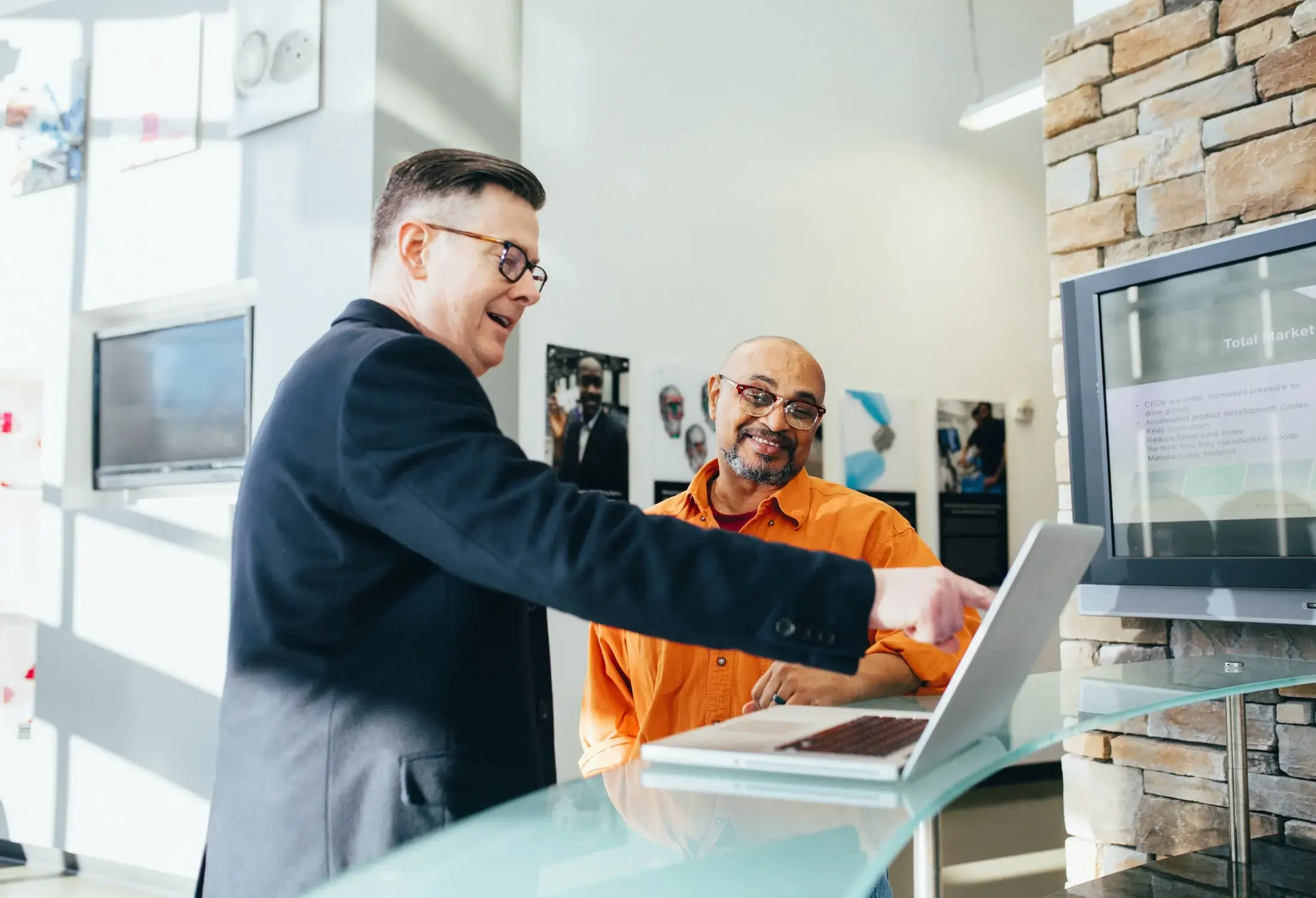 Man showing another man something on his laptop.